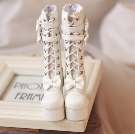 a pair of white boots with bows on a white frame